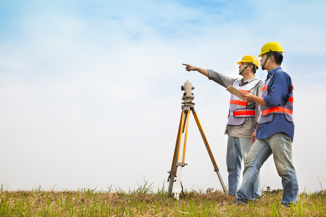 Surveyor engineer making measure with partner on the field