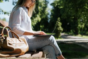 Young,Smiling,Woman,Working,On,Laptop,While,Sitting,,Typing,On