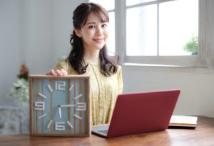 Smiling,Asian,Woman,Holding,A,Clock.