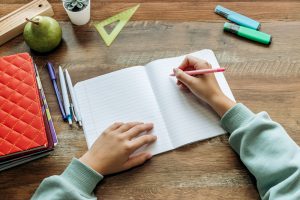 Schoolchild,Writing,In,A,Notebook,At,Home,At,His,Desk.completing