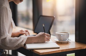 Close,Up.,Businesswoman,Hand,Taking,Notes,Working,At,A,Cafã©.