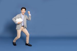 Portrait,Of,Happy,Asian,Businessman,Holding,White,Piggy,Bank,Isolated