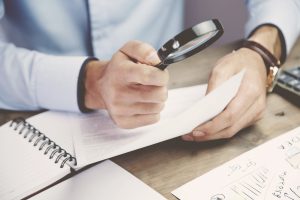 Businessman,Looking,Through,A,Magnifying,Glass,To,Documents