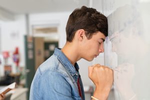 Disappointed,University,Student,Leaning,On,Whiteboard,With,Closed,Eyes.,Tired