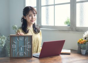 Smiling,Asian,Woman,Holding,A,Clock.