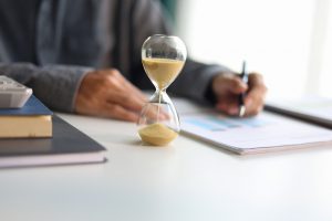 Selective,Focus,On,Sand,Clocks.,Businessman,Working,At,Office,Desk.