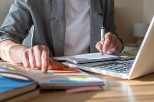 Business,Person,Writing,Notes,In,A,Spiral,Notebook,And,Pointing